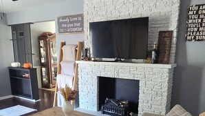 Un salon avec une cheminée en pierre, un téléviseur fixé au-dessus, un canapé et une table basse.