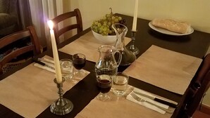Une table à manger décorée avec des bougies, un panier de fruits, une carafe et une assiette de pain.