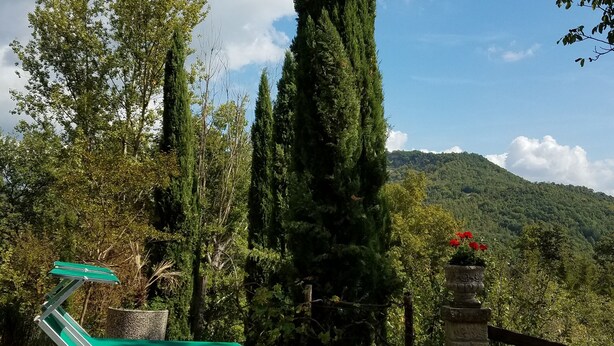 Un fauteuil vert est posé sur une plateforme en pierre, d’où l’on peut admirer un paysage de montagne et de arbres.