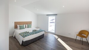Una camera da letto con un letto, una sedia e una vista attraverso una porta.