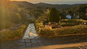 A stone pathway leading to a scenic view of a hillside with a sunset. - Parc du Montnegre, villa with magnificent sea view (Tordera)