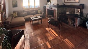 A living room with a sofa, coffee table, and fireplace. - Parc du Montnegre, villa with magnificent sea view (Tordera)
