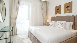 Hotellihuone, jossa on sänky, työpöytä, peili ja verhot.