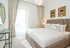 A hotel room with a bed, a desk, a mirror, and curtains.