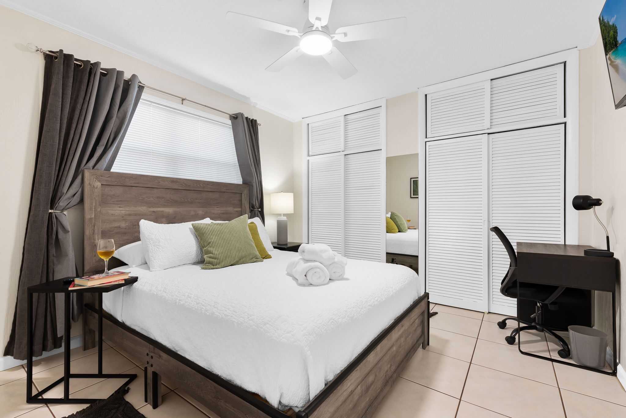 Een netjes opgemaakt slaapkamer met een bed, nachtkastje, lamp en een bureau met een stoel.