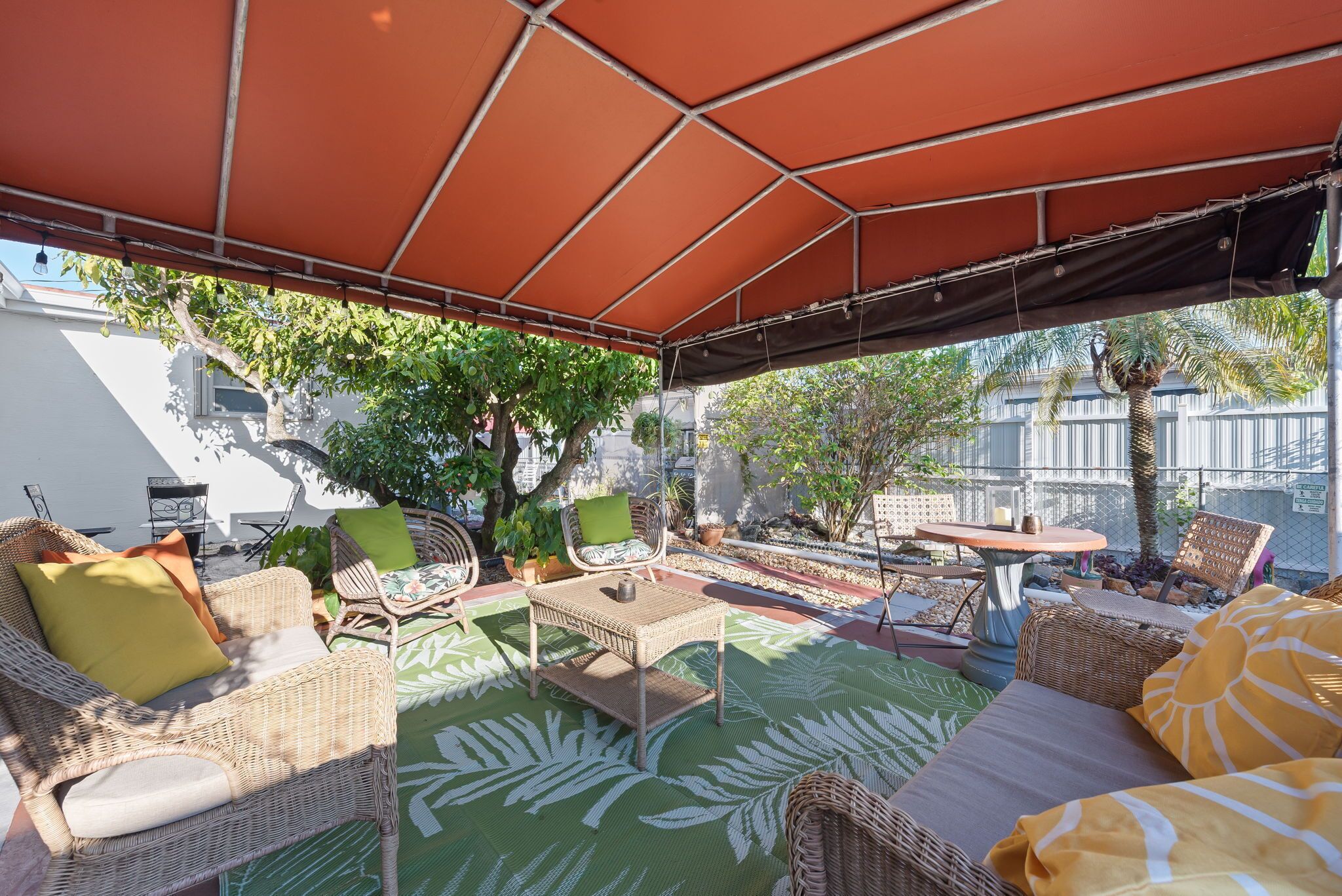 Een terras buiten met rieten meubels, een tafel en een overdekt gedeelte.