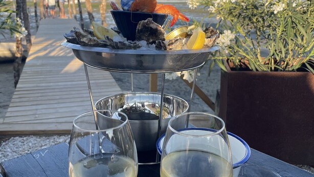 A table with two glasses of white wine, a metal tray with seafood and a bowl, and a wooden deck with a railing. - Family home with large terrace 100m from the beach, (Lège-Cap-Ferret)