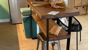 A kitchen with a wooden table, a trash bin, a refrigerator, and a staircase. - Family home with large terrace 100m from the beach, (Lège-Cap-Ferret)