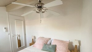 A bedroom with a bed, a ceiling fan, a door, and bedside lamps. - Family home with large terrace 100m from the beach, (Lège-Cap-Ferret)