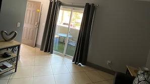 A living room with a sofa, a small table, a heart-shaped decoration, and a sliding glass door leading to an outdoor area. - Cozy 2-bedroom condo with AC, WiFi in wonderful Las Vegas with strip view (Las Vegas)