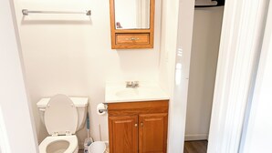 Een badkamer met toilet, wastafel en houten kast.