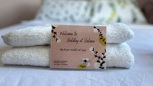A neatly made bed with folded white towels and a welcome card on top. - Welcome to Solstay, a get go place to stay Cozy 1-bedroom condo near Alabang (Muntinlupa)