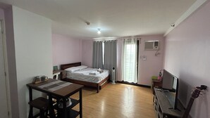 A hotel room with a bed, a desk, a chair, a television, and a guitar. - Welcome to Solstay, a get go place to stay Cozy 1-bedroom condo near Alabang (Muntinlupa)
