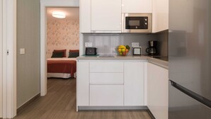 A compact kitchen with white cabinets, a microwave, a coffee maker, and a fruit bowl on the countertop. - Apartment in Telde Near Playa de Melenara (Telde)