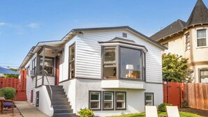 Une maison à deux étages, dotée d’une grande baie vitrée, d’un porche à l’avant et d’un escalier bien visible.