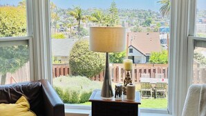 Une pièce avec vue sur le paysage urbain, un canapé en cuir, une petite table avec une lampe et une statue.