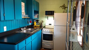 Une cuisine avec des meubles de rangement bleus, un four à micro-ondes, un réfrigérateur et une cuisinière.