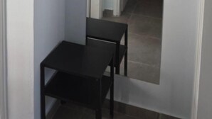 A narrow hallway with a mirror reflecting a room. A small table is placed against the wall. - Chrisa's Apartments Mesologgi (Mesolongi)