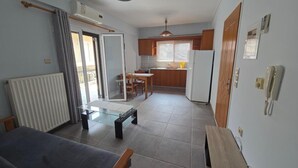 A compact living space with a dining area, kitchenette, and a sliding glass door leading to a balcony. - Chrisa's Apartments Mesologgi (Mesolongi)