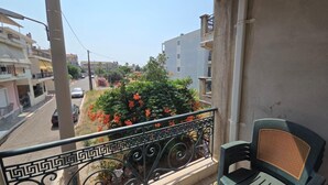 A balcony with a view of a street, a parked car, and a building with balconies. - Chrisa's Apartments Mesologgi (Mesolongi)