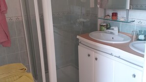 Une salle de bain avec une douche à parois de verre, un lavabo blanc et un miroir au-dessus.