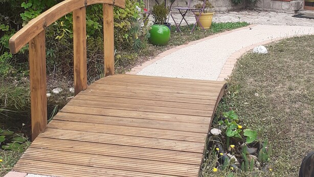Un pont en bois menant à un bâtiment en pierre doté d’un balcon.