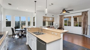 A spacious kitchen with a central island, a dining area, and large windows.