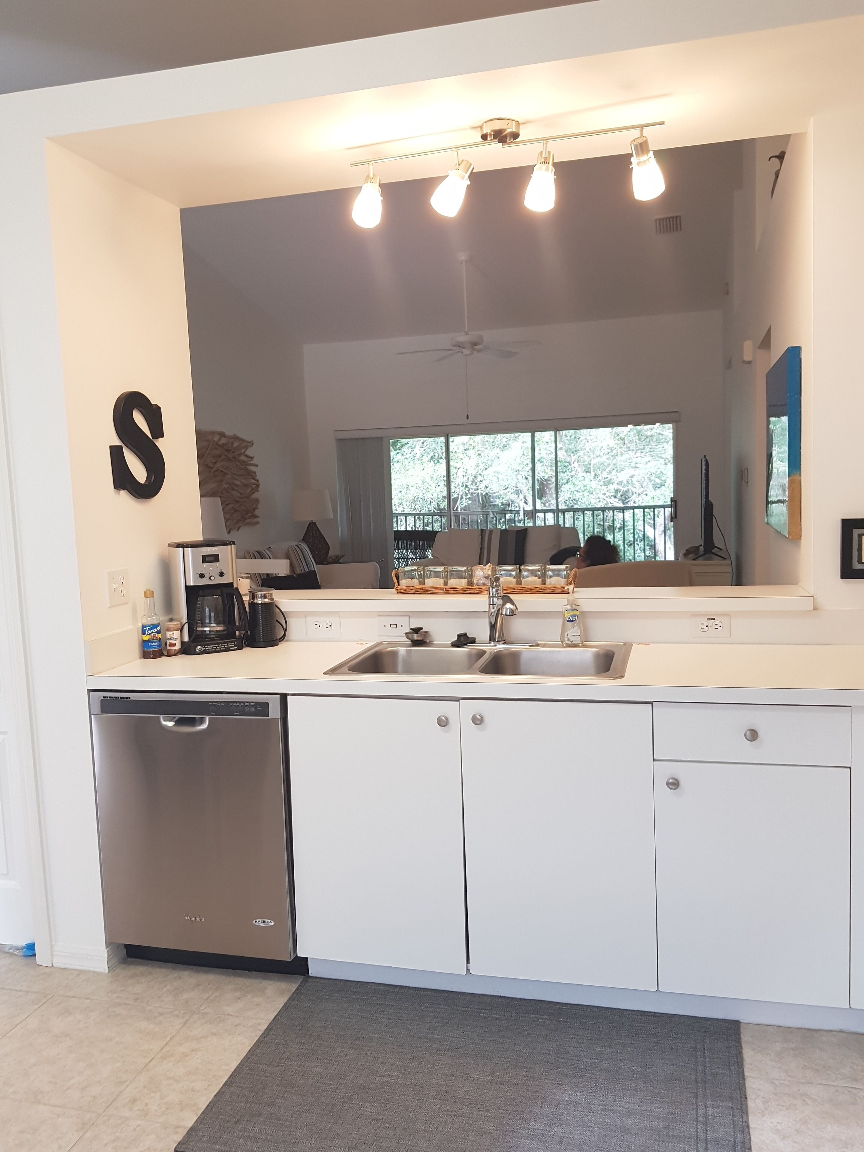 Una cocina moderna con armarios blancos, lavavajillas de acero inoxidable, un lavabo y un ventilador de techo.