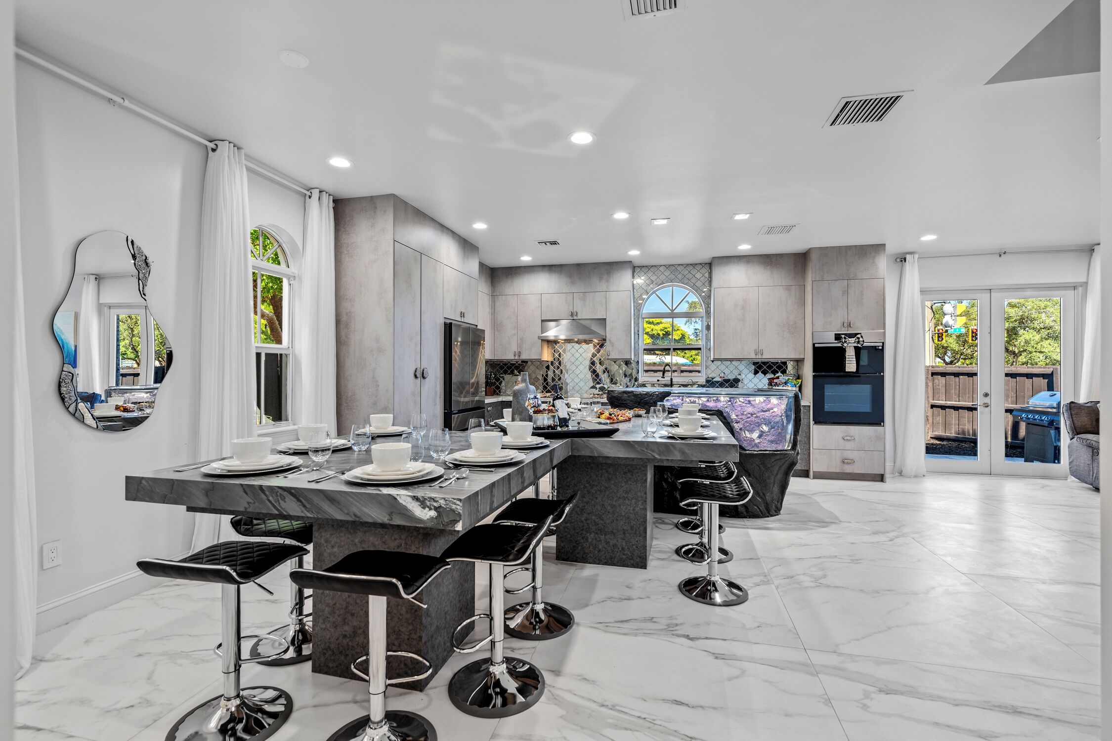 A modern kitchen with a marble countertop, black bar stools, and a large island.