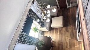 Un salon moderne avec un plancher en bois, une table basse ronde, un canapé et un fauteuil sphérique original. Un lustre à plusieurs ampoules est suspendu au plafond.