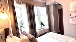 Une chambre d’hôtel avec un lit, une lampe de chevet, une fenêtre avec des rideaux et une vue sur l’extérieur.