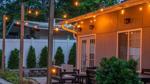 Eine Außenpatio-Terrasse mit Lichterketten, Holzstühlen und einer Steinwand.