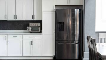 A modern kitchen with white cabinets, a stainless steel refrigerator, and a built-in oven.