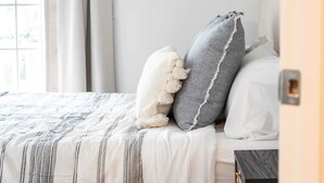 Ein ordentlich bezogenes Bett mit einem gestreiften Bettbezug, zwei Kissen und einem Nachttisch mit einer Lampe.