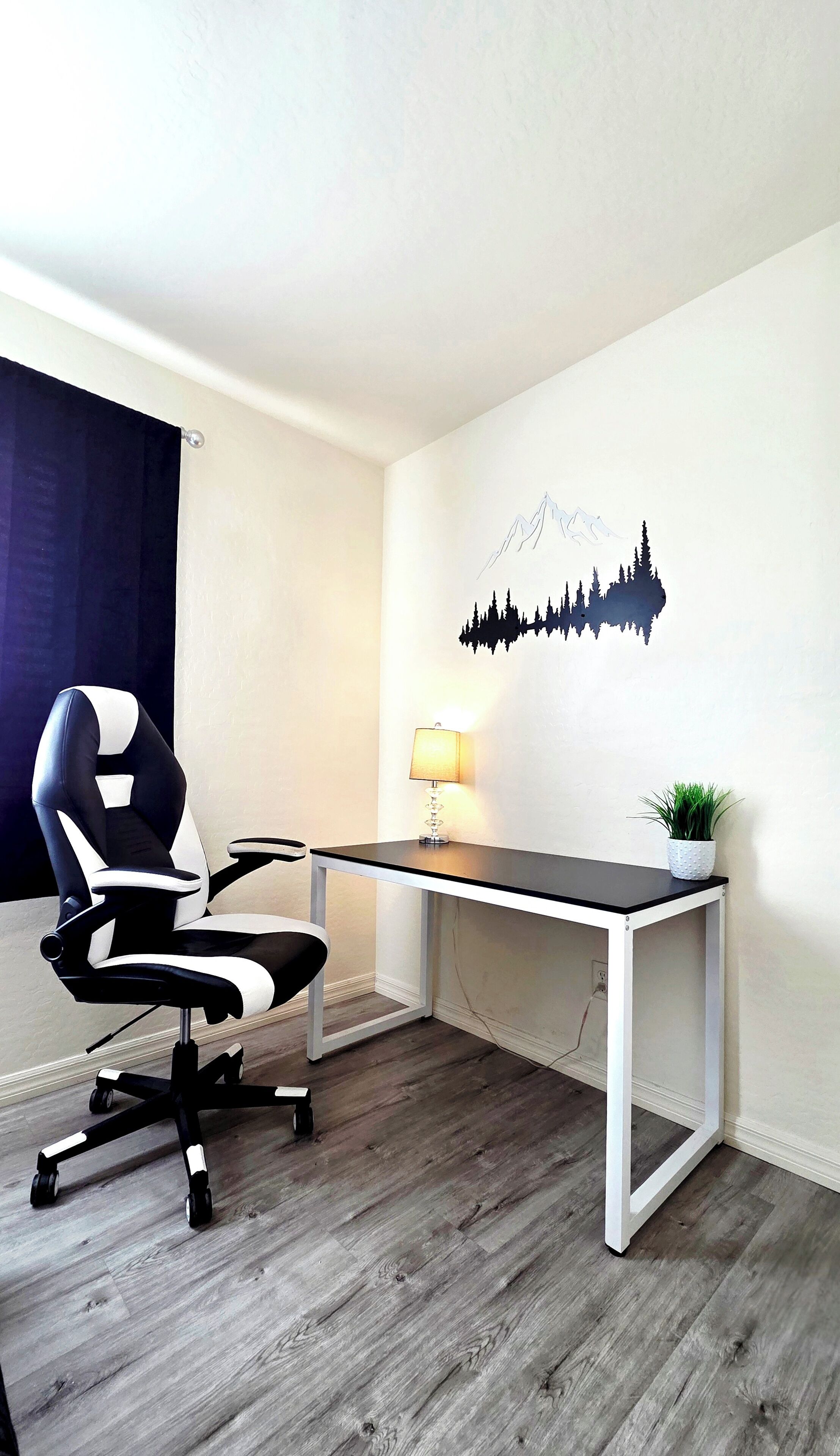 A modern office space with a desk, office chair, lamp, and a wall decoration.