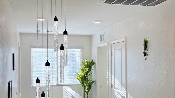 Una escalera con barandilla blanca, un aplique colgante y una planta.