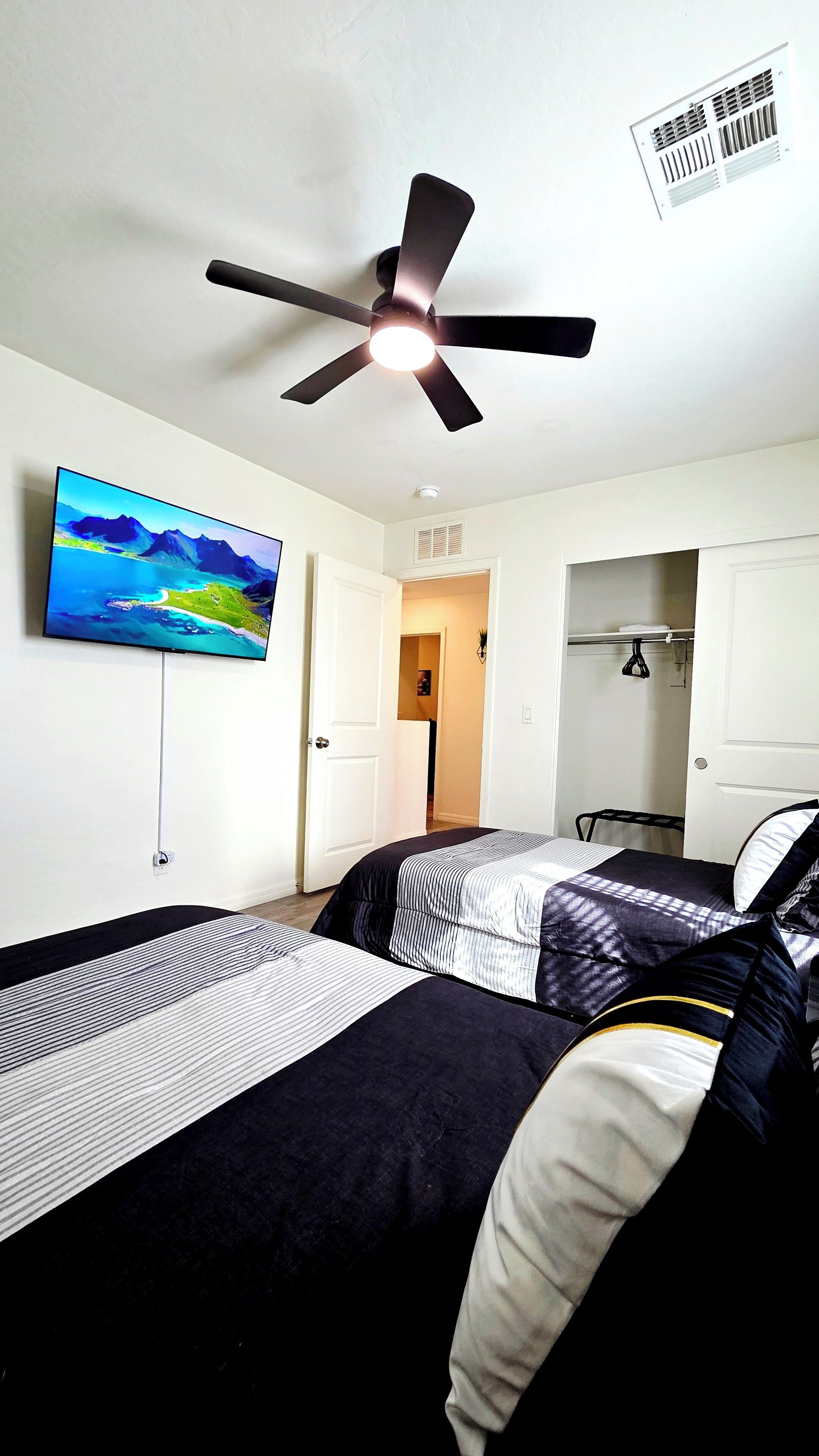 A hotel room with two beds, a ceiling fan, a TV, and a wardrobe.