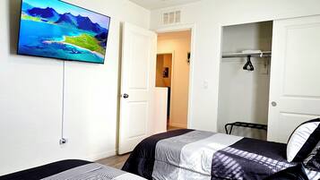 A hotel room with two beds, a ceiling fan, a TV, and a wardrobe.