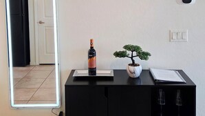 Una habitación con un armario negro, un reloj de pared, una planta en maceta y una botella de vino.