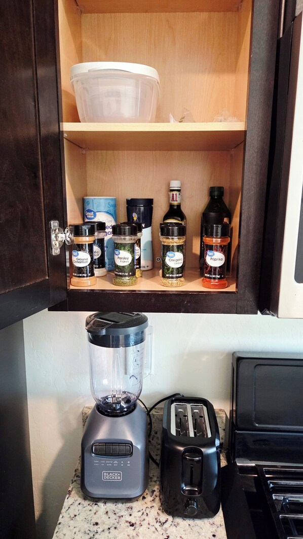 A kitchen with a blender, toaster, and spice rack.