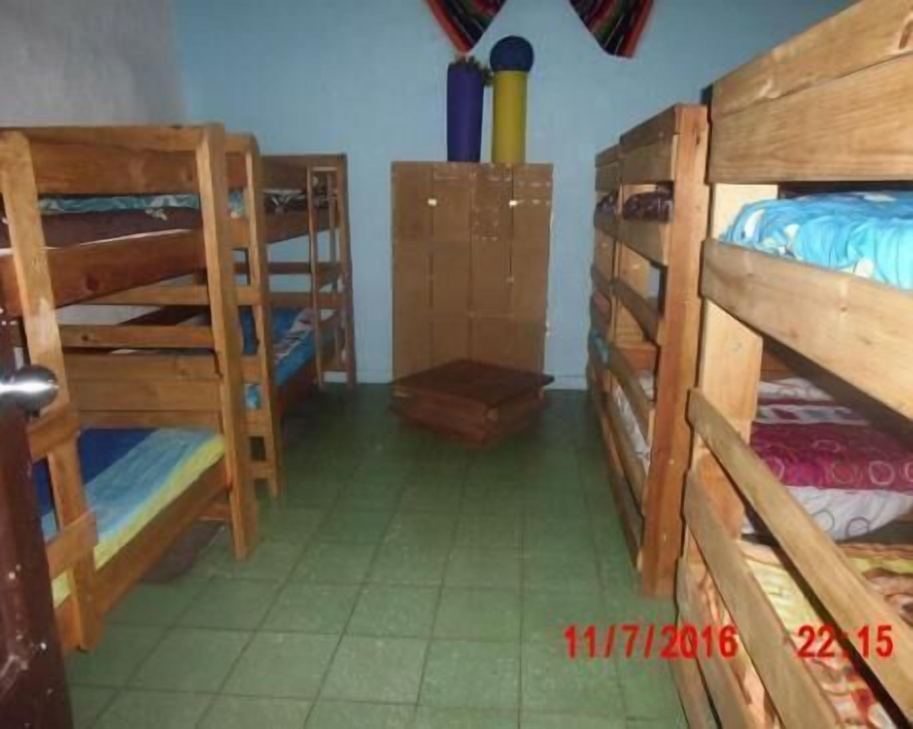 A dormitory room with bunk beds, a wardrobe, and a small storage box.