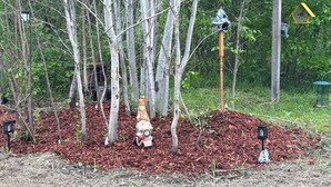 A garden with a small statue, a birdhouse, and a wooden post. - Campground. Off grid camping. (Geneva)