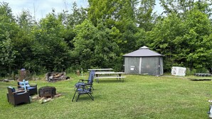A backyard with a picnic table, two lawn chairs, a shed, and a small garden area. - Campground. Off grid camping. (Geneva)
