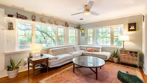 A living room with a sectional sofa, a glass coffee table, and a ceiling fan.