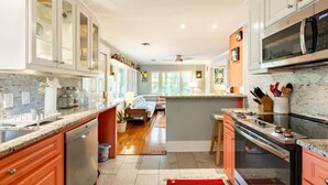 A modern kitchen with white cabinets, a dishwasher, a stove, and a microwave.