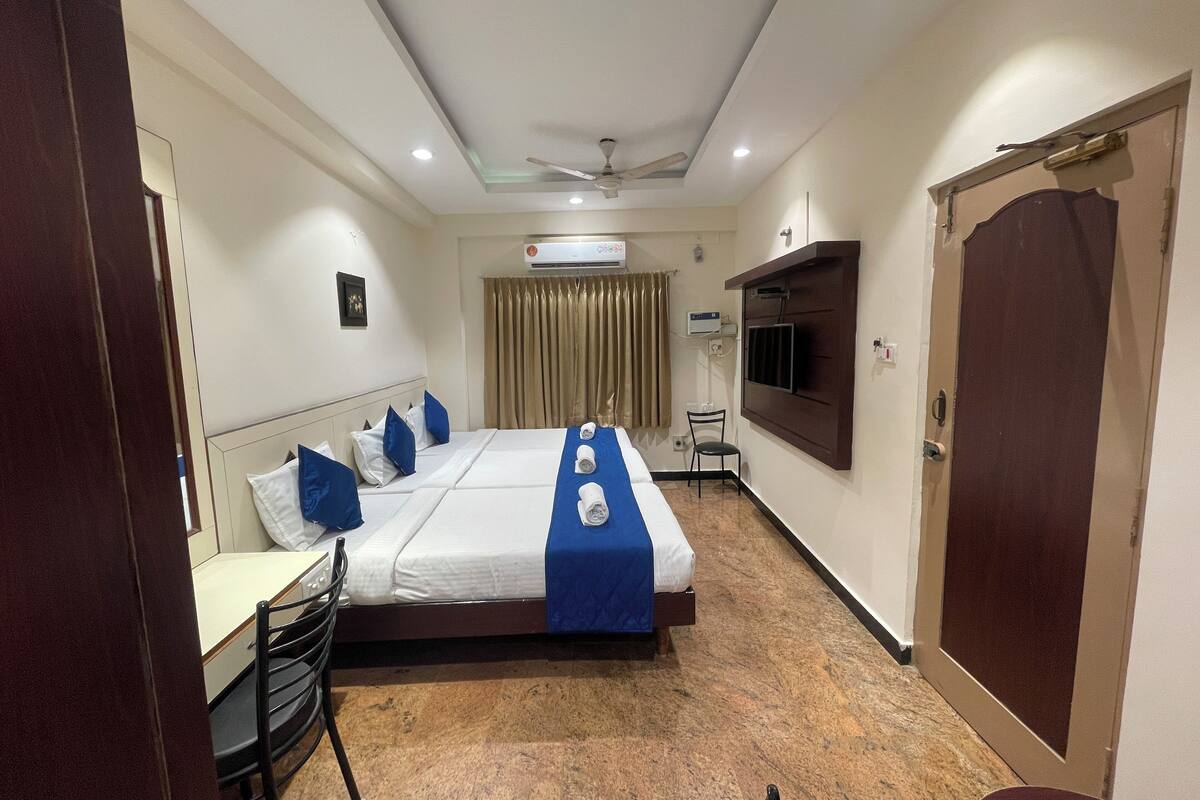 Ein Hotelzimmer mit einem Bett, einem Schreibtisch, einem Sessel, einem an der Wand befestigten Fernseher und einem Kleiderschrank.