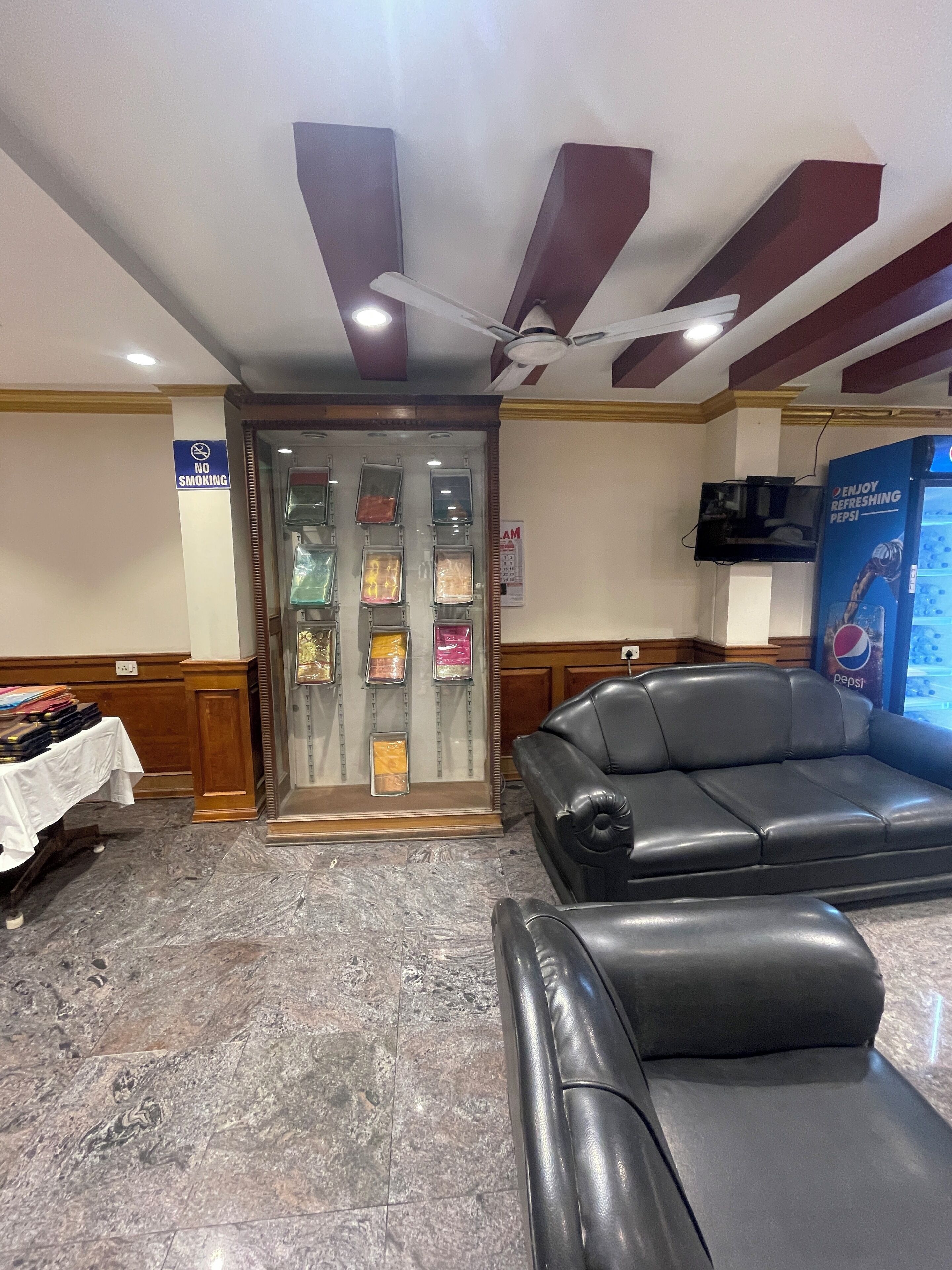 A lobby with a seating area, a no smoking sign, a wall-mounted clock, and a Pepsi vending machine.