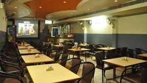 Une salle de conférence équipée de plusieurs tables et chaises, d’un grand écran et d’un projecteur.