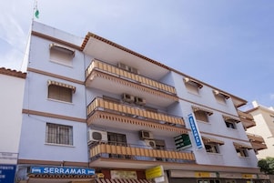 A multi-story building with balconies, air conditioning units, and a sign for 'SERRAMAR'.