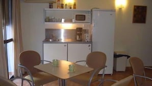 A compact kitchen with a microwave, coffee maker, and cabinets. There are four chairs around a small table. - Serramar (Benalmádena)